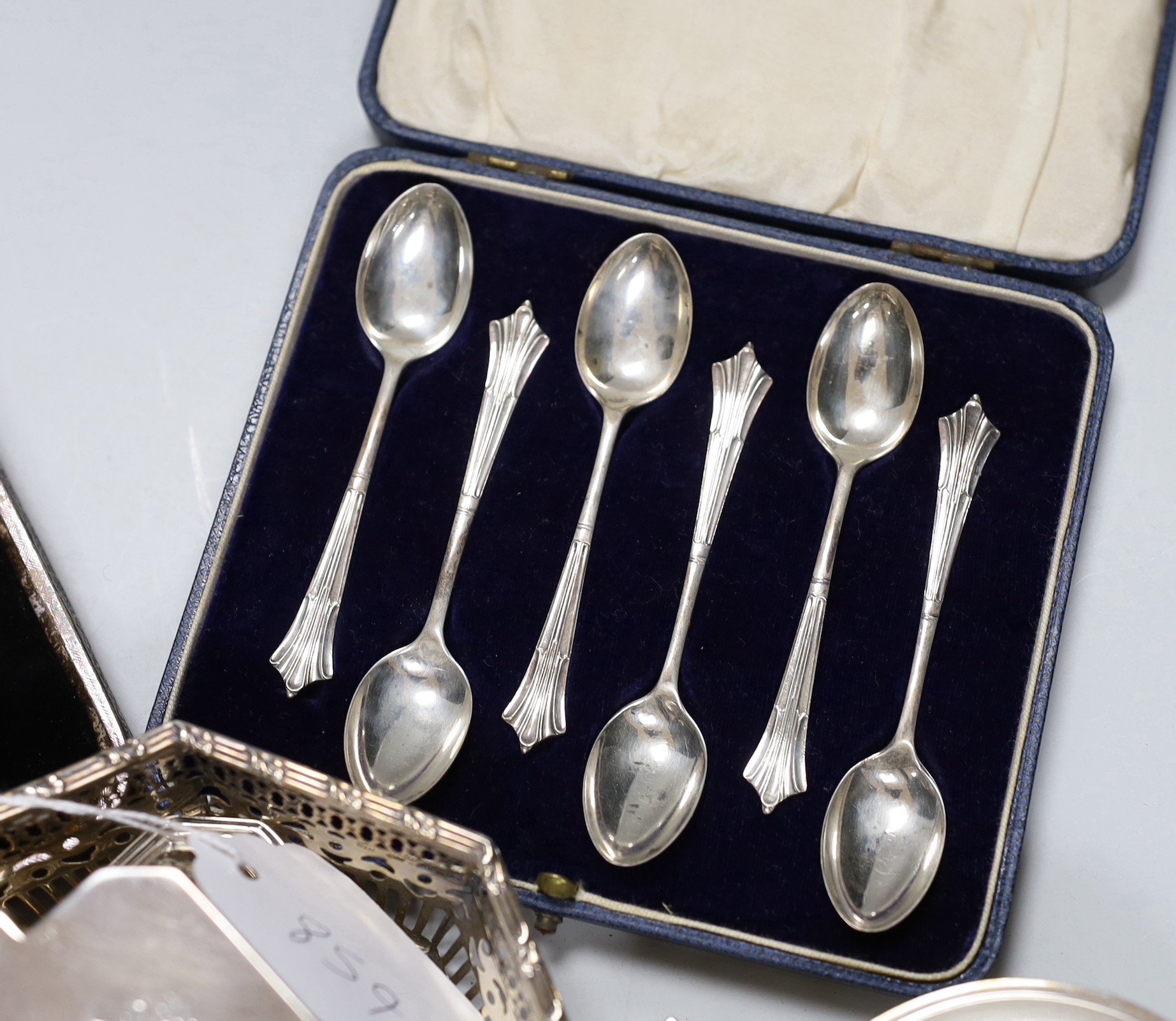 Assorted silver ware including two cased sets of six teaspoons, one with tongs, a christening mug, pierced sterling octagonal bowl, a Scottish silver quaich, inkwell, salt, three napkin rings, enamelled pill box, sifter